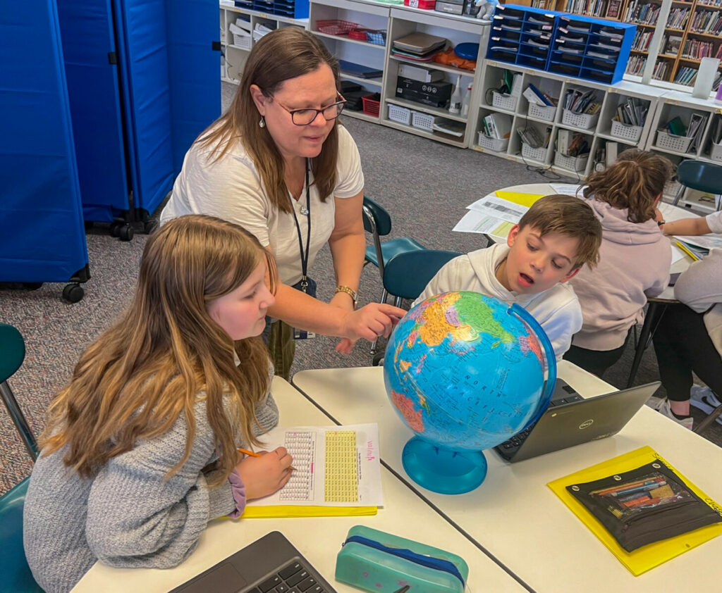 teacher with students with globe at table