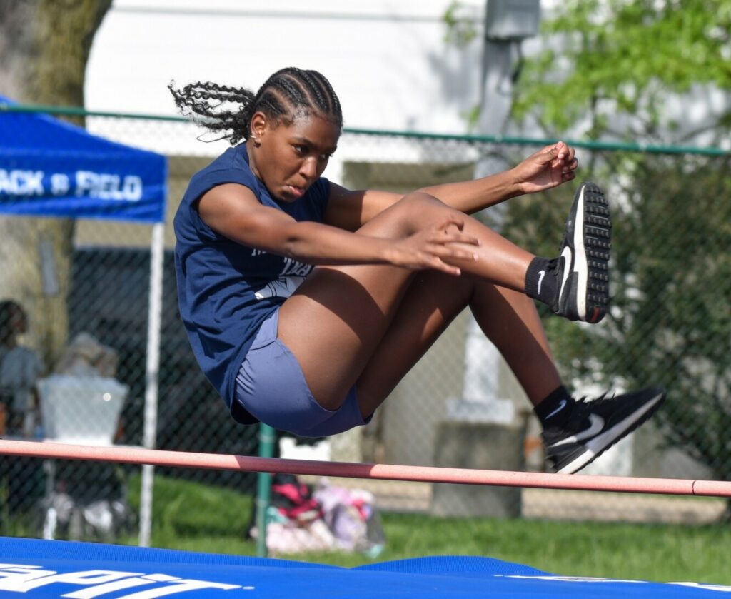 athletic female student doing high jump