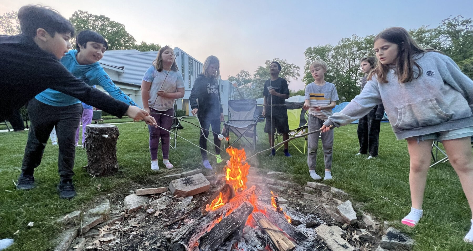 Students roasting marshmallows around campfire